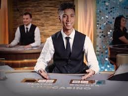 Dealer kasino live online sedang membagikan kartu dengan latar belakang studio profesional